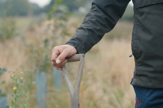 Close up of a person holding a wooden handled spade
